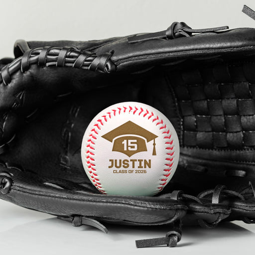 A personalized baseball with a graduation cap with number 15 and the text "JUSTIN CLASS OF 2026", placed in a black baseball glove.