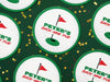 Custom round pulpboard coasters are shown spread out across a dark green surface covered in red and gold star confetti. The custom coasters features a green border, golf ball, a red flag, and golf hole illustration and bold text across the center that can be customized with a name and lounge name.
