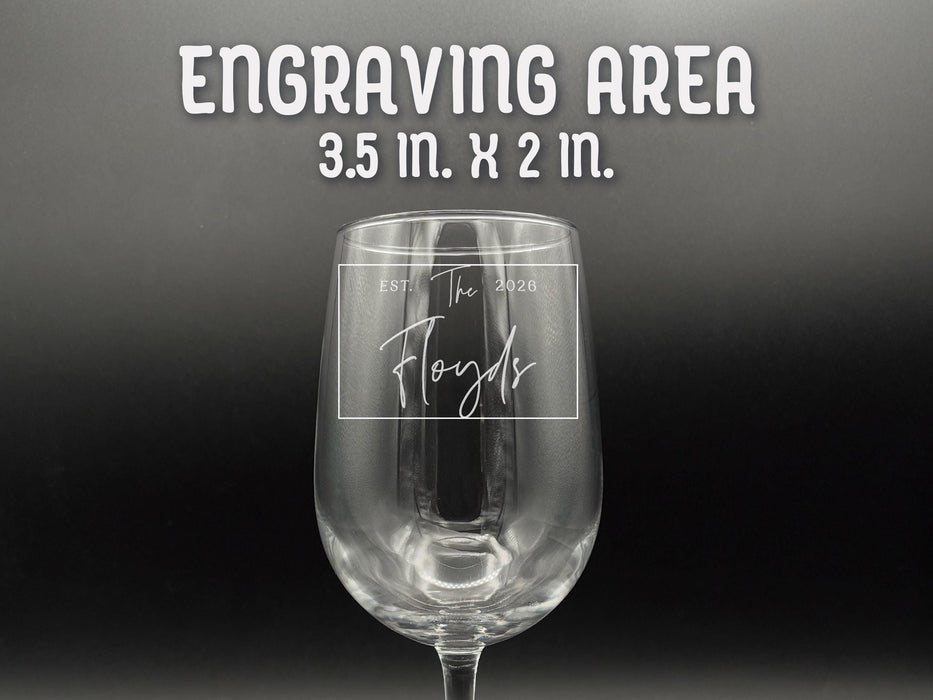 Engraving Area: 3.5in x 2in. One wine glass sits in front of black background. The glass has Last Name and Established Date design engraved on it.