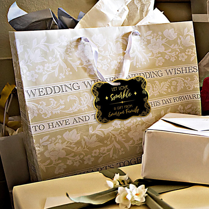 Gold foil “Let Love Sparkle” wedding gift tag attached to elegant wedding gift packaging. Styled with wrapped presents and neutral wedding décor for gifting inspiration.