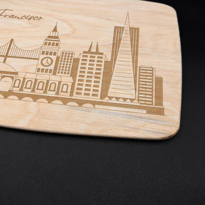 Close-up of the engraved San Francisco cityscape showing the bridge, skyline buildings, and natural maple wood grain.