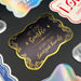 Close-up of a personalized “Let Love Sparkle” wedding gift tag on gold foil with black ink. The elegant foil cardstock tag features custom sender names with decorative wedding-inspired details.