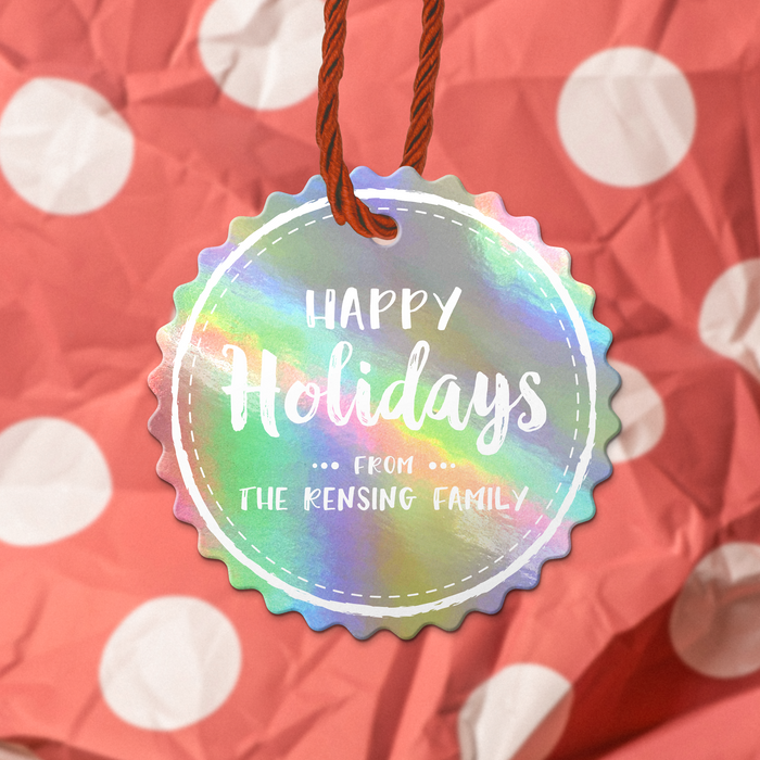 A rainbow hang gift tag with the text "Happy Holidays" UV printed on it, hanging from a string against a background of red and white polka dots.