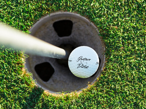 Titleist golf ball shown in a golf course hole.