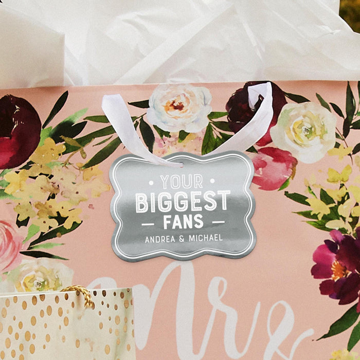 Floral wedding-themed display featuring a personalized “Your Biggest Fans” gift tag in metallic silver foil. Styled with soft flowers and romantic wedding décor accents.