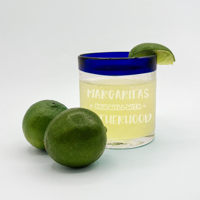 Blue rim margarita glass with “Margaritas Pair Well With Motherhood” UV etched design and fresh limes.