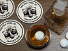 A full bourbon glass is shown next to a decanter while sitting on a wooden table. A golf ball rests in the glass. Custom coasters and golf balls can be seen on the table as well. A custom coaster is also placed underneath the glass. The custom coasters feature a golf ball centered between two whiskey glasses clinking together and splashing out with customizable text wrapping around the illustration. The coaster design is printed in black.