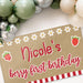 Large personalized first birthday banner hanging with party decorations featuring berry themed graphics and custom printed name.