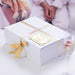 White gift box wrapped with satin ribbon and decorated using a personalized “Mr. & Mrs.” gold foil wedding gift tag. Styled as premium wedding and bridal shower gift packaging.