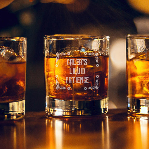 Warm bar-style lifestyle image of a personalized whiskey glass with glowing ambient lights in the background, featuring the “Caleb’s Liquid Patience” engraved design. The rich whiskey tones and soft lighting create a premium lounge-inspired presentation.
