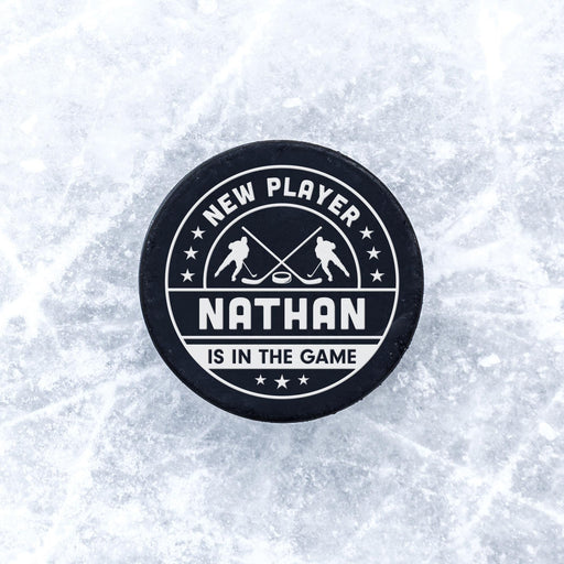 Personalized hockey puck with a white UV printed “New Player” birth announcement design displayed on a frosty ice background.