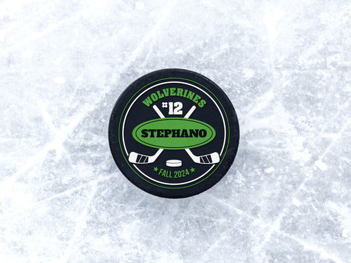 Hockey puck on ice rink with a green player and team name design with a hockey stick design with the words Wolverines, 12, Stephano, Fall 2024