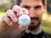 Groom holds Titleist golf ball with Elegant Initials & Date design.