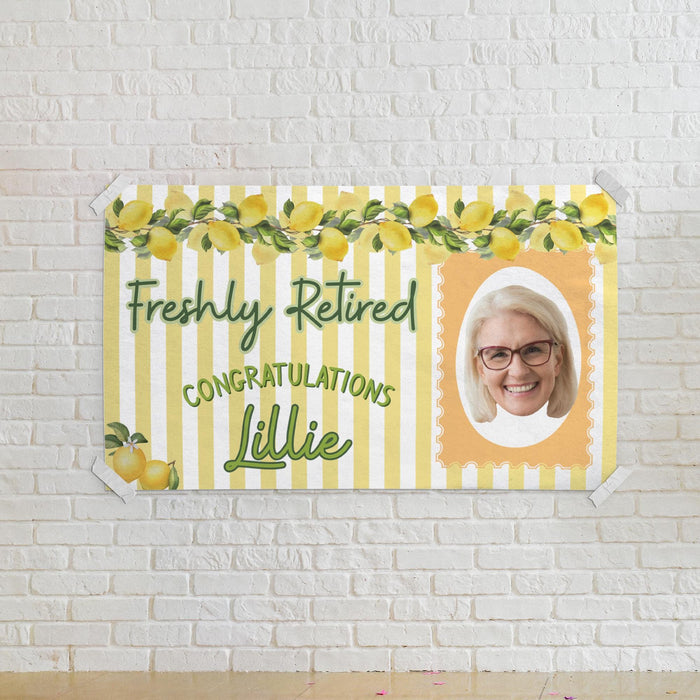 Lemon-themed retirement banner mounted on a white brick wall. Features a custom photo, retiree name, and bright retirement party design.