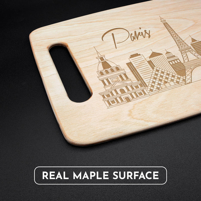 Angled view of the Paris maple cutting board with handle, engraved skyline, and natural wood grain.