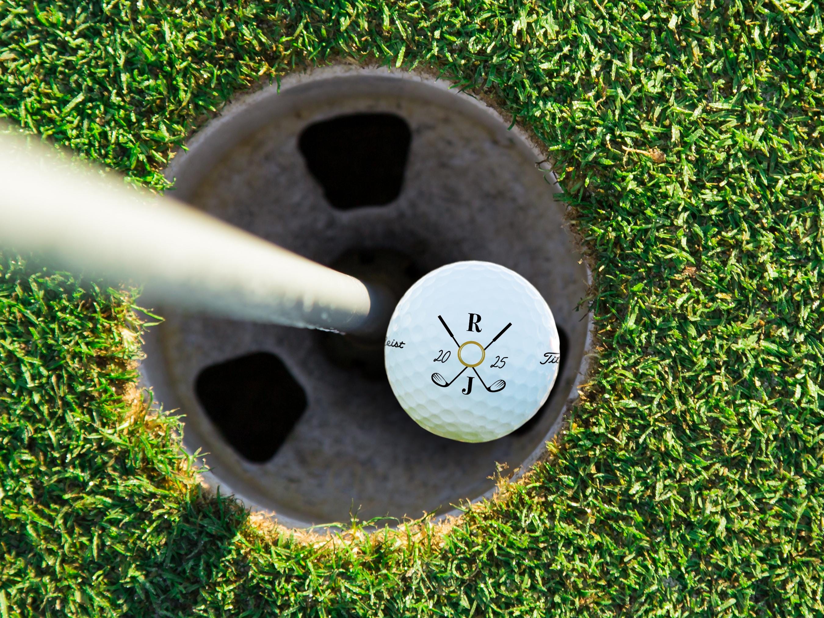 A close-up of a golf ball with a personalized design on it, placed on a grassy surface.