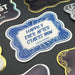 Flat lay photo featuring the “Happily Ever After Starts Now” wedding gift tag on a white glitter tag. The personalized tag is displayed among other custom gift tag designs on a dark background.