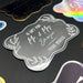 Close-up of a personalized “Mr. & Mrs.” wedding gift tag in metallic silver foil on black cardstock. The custom tag features the couple’s last name and sender name in an elegant handwritten style.