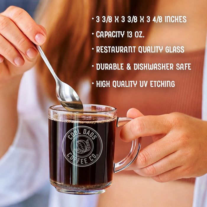 A person is holding a glass mug with a message engraved on it. The image is accompanied by a text overlay that reads • 3 3/8 x 3 3/8 x 3 4/8 inches • Capacity 13 oz. • restaurant quality glass • durable & dishwasher safe • high quality uv etching