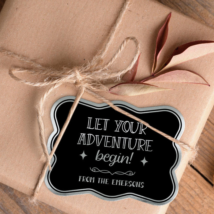 Personalized “Let Your Adventure Begin” wedding gift tag attached to kraft paper wrapping with natural twine. The metallic foil finish and decorative details create a keepsake-style presentation.