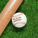 Baseball sits on grass next to baseball bat. Baseball has Established Date Father's Day design engraved on it.