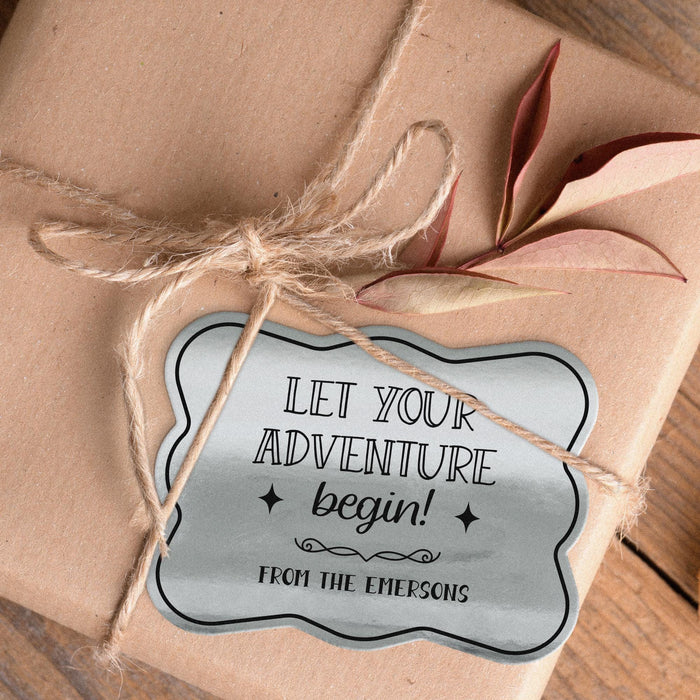 Personalized “Let Your Adventure Begin” wedding gift tag attached to kraft paper wrapping using natural twine. The metallic silver foil finish creates an elegant keepsake-style presentation.