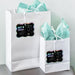White gift bags with tissue paper decorated using personalized Bear Couple wedding gift tags in rainbow foil style. Perfect for wedding welcome bags, party favors, or bridal shower gifts.
