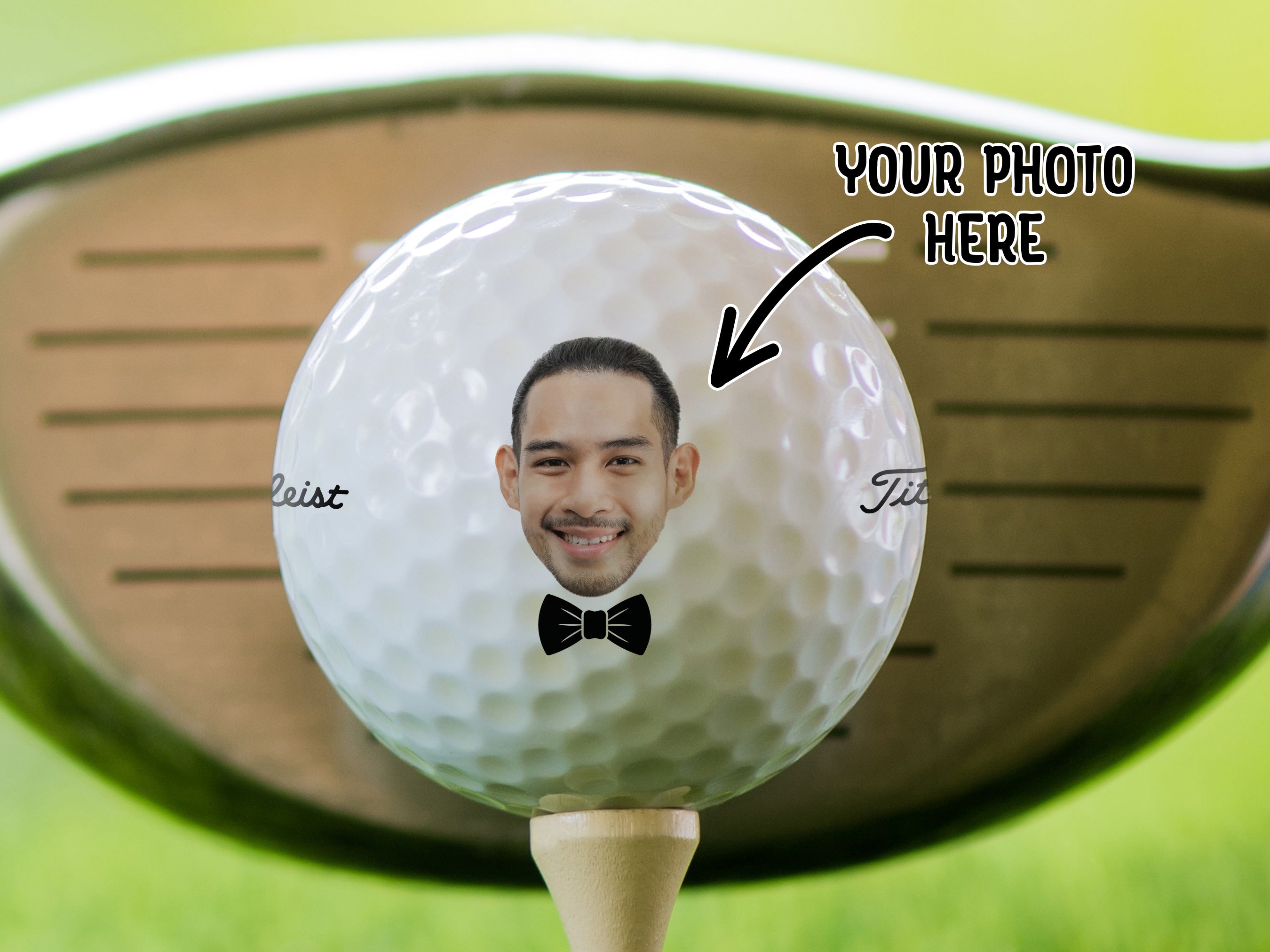 A golf ball with a man's face printed on it, placed on a grassy surface.