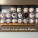 A collection of baseballs and a wooden mini baseball bat displayed on a shelf, with the caption "Crafted to Last. Made to Display."