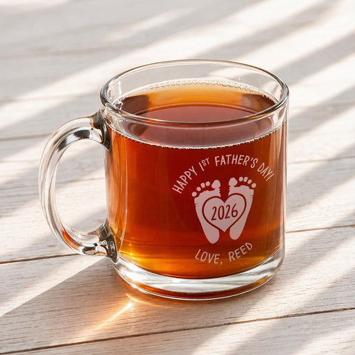 A glass mug filled with a brown liquid, likely tea, sits on a wooden surface.