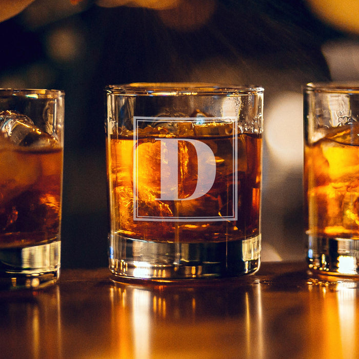 Warm bar-style lifestyle image with glowing ambient lights in the background. The personalized glass is filled with whiskey and ice, highlighting the elegant engraving.