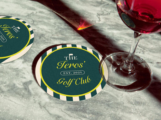 Custom round pulpboard coasters are shown sitting on a marble surface with a wine glass next to them. The custom coasters feature design printed with script and serif customizable text and striped background.