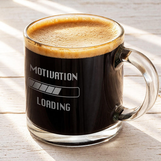 A glass mug filled with a dark beverage, likely coffee, with a motivational message engraved on it.
