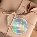 A brown gift box tied with twine and adorned with a Christmas gift tag that reads "Happy Holidays".