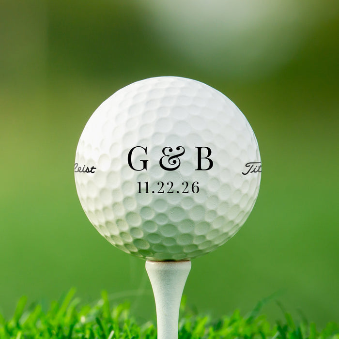 A white golf ball with the letters "G&B" printed on it, placed on a grassy surface.