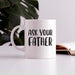 White ceramic “Ask Your Father” mug styled on a desk beside an open book and plant. A clean lifestyle setup showing the mug as a perfect daily coffee companion.