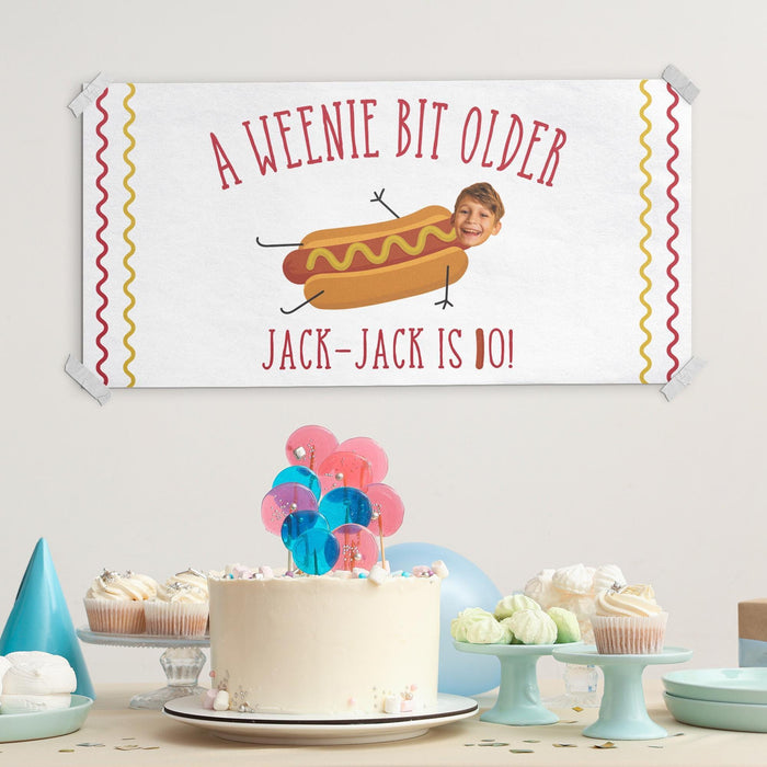 Personalized "A Weenie Bit Older" birthday banner displayed with cake and party decorations.