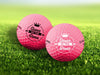 Two golf balls with the phrase "Queen of the Green" design printed on them, placed on a grassy field.