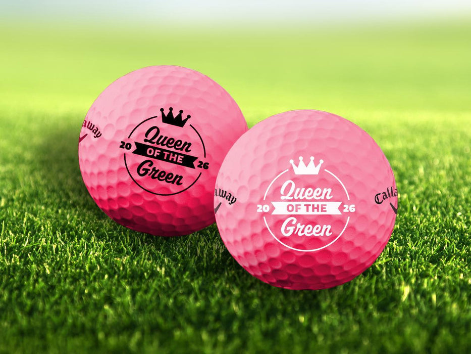 Two golf balls with the phrase "Queen of the Green" design printed on them, placed on a grassy field.