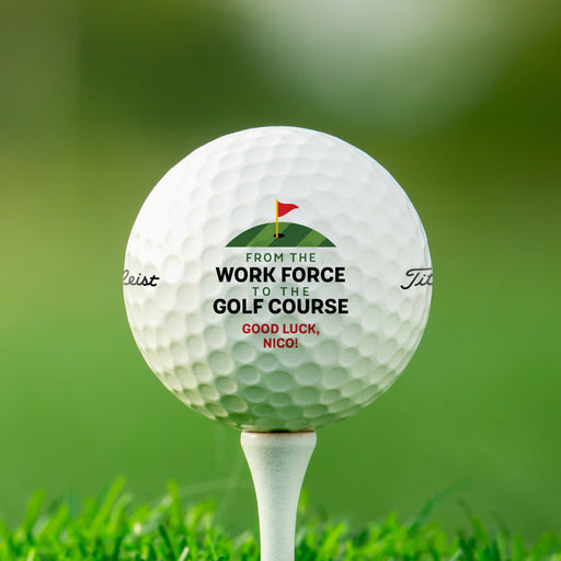 Single white Titleist golf ball with From the Work Force to the Golf Course design on white golf tee with golf course grass in the background