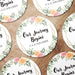 Personalized floral Save the Date coasters shown in a wedding favor arrangement. Features a floral wreath design with custom names and wedding date.