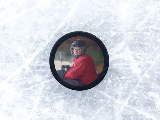 single custom photo hockey puck with a kid hockey player in a red jacket and helmet photo sitting on top of ice