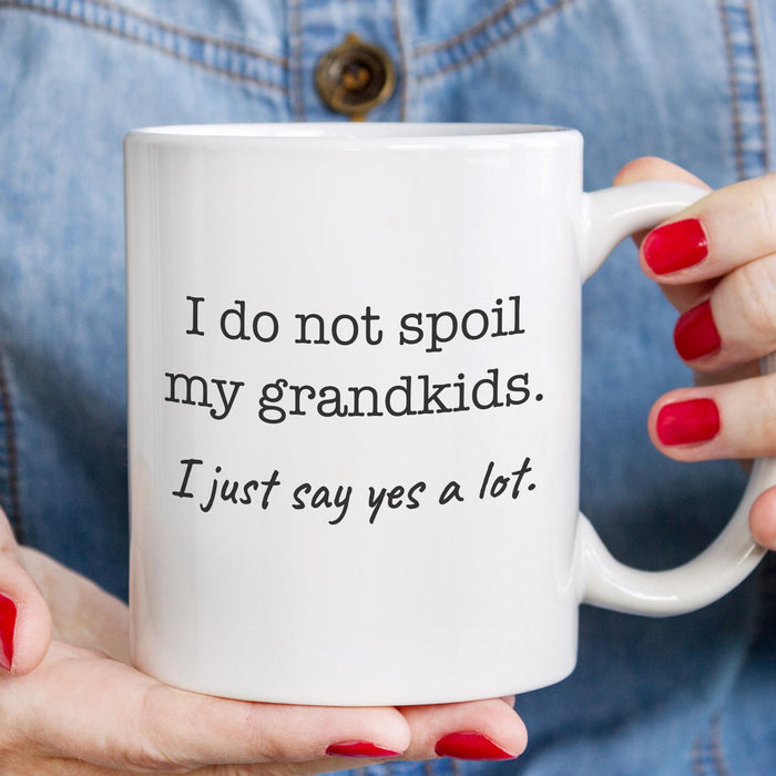 Funny grandkids coffee mug held in hand with black printed quote.