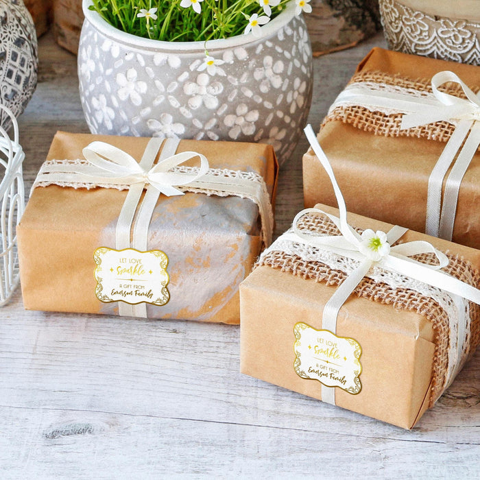 Wrapped wedding gifts tied with ribbon and decorated using personalized “Let Love Sparkle” foil gift tags. The tags add a polished finishing touch to bridal shower and wedding presents.