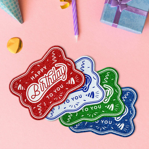 Four birthday rectangle tags in glitter blue, glitter red, glitter green, and glitter white.