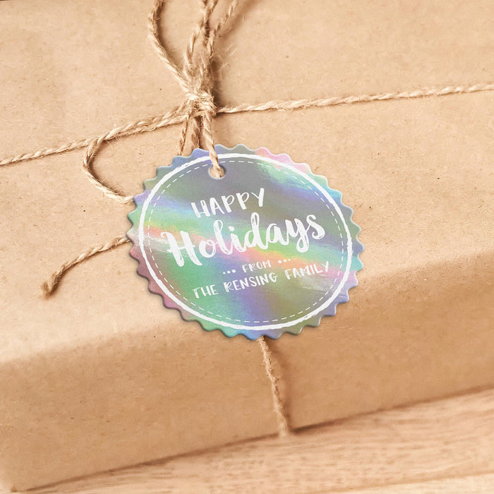 Round personalized Happy Holidays hang tag tied to a kraft paper wrapped gift with natural twine on a warm neutral background.