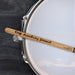 A drumstick with the words "Keep marching forward" engraved on it, resting on a drum set.