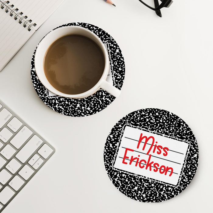 Lifestyle image of personalized teacher coaster on a desk next to coffee and workspace items. Demonstrates everyday classroom use.