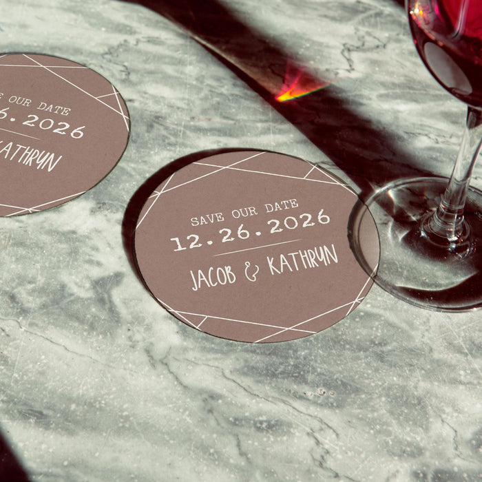 Personalized Save the Date coaster displayed beside a wine glass. Custom wedding favor featuring names and wedding date.