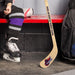 Lifestyle image of a hockey player in skates holding a personalized mini hockey stick with a team logo printed on the blade.